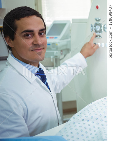 Doctor operating medical equipment in hospital, ensuring patient care and safety 128698437