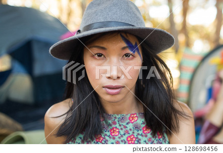 Woman in hat with face paint enjoying outdoor music festival atmosphere 128698456