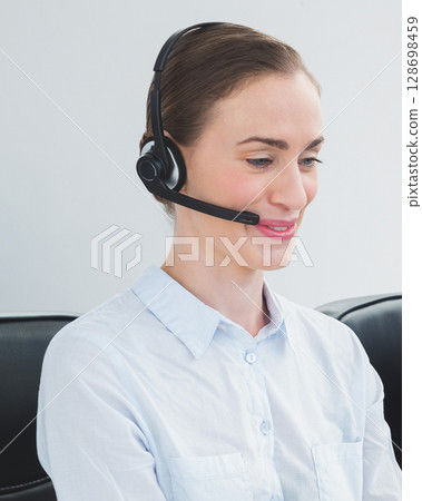 Wearing headset, customer service representative assisting clients with smile 128698459