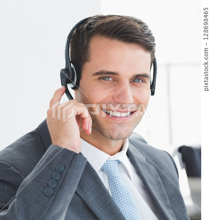 Smiling businessman using headset for communication in modern office setting 128698465