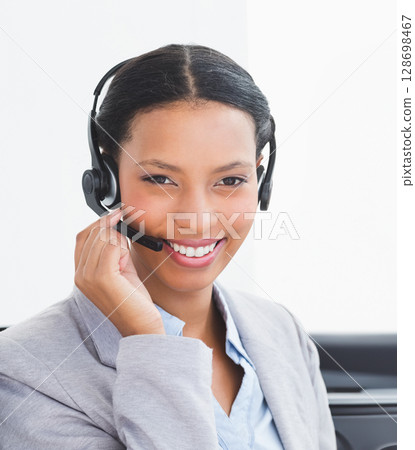 Using headset, businesswoman providing customer service in office, smiling warmly 128698467
