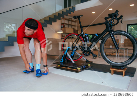The triathlete putting on his sneakers and preparing for his home bike training . 128698605