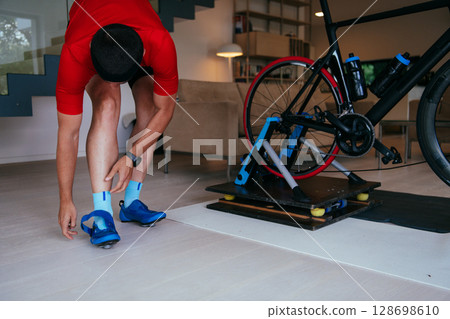 The triathlete putting on his sneakers and preparing for his home bike training . 128698610