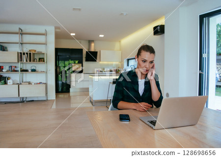 Woman sitting in living room using laptop looking at cam talk by video call with business friend relatives, head shot. Job interview answering questions Woman sitting in living room using laptop looking at cam talk by video call with business friend relatives, head shot. Job interview answering questions 128698656