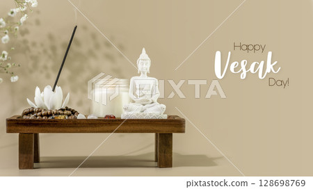 Vesak, Buddha Day holiday card. Still life with Buddha statue, candle, aroma stick on wooden podium with white flowers, shadows and inscription Happy Vesak Day 128698769