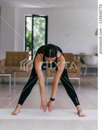 Young Beautiful Female Exercising, Stretching and Practising Yoga with Trainer via Video Call Conference in Bright Sunny House. Healthy Lifestyle, Wellbeing and Mindfulness Concept 128698778