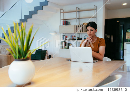 Woman sitting in living room using laptop looking at cam talk by video call with business friend relatives, head shot. Job interview answering questions 128698840