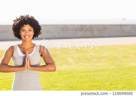 Practicing African American woman pressing hands together on waterfront lawn by seawall, copy space Practicing African American woman pressing hands together on waterfront lawn by seawall, copy space 128699080