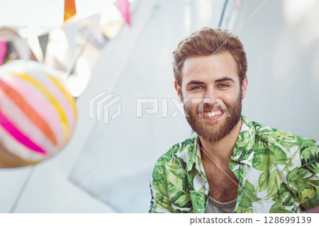 Smiling bearded man standing in backyard, with festive bunting flags and paper lantern, copy space 128699139