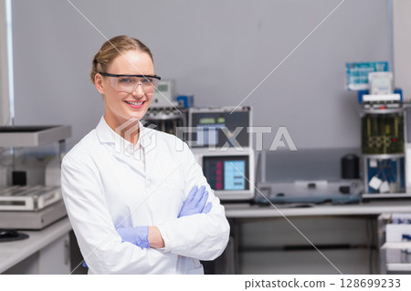 Smiling female scientist crossing arms in modern lab, with analyzers and monitors, copy space Smiling female scientist crossing arms in modern lab, with analyzers and monitors, copy space 128699233