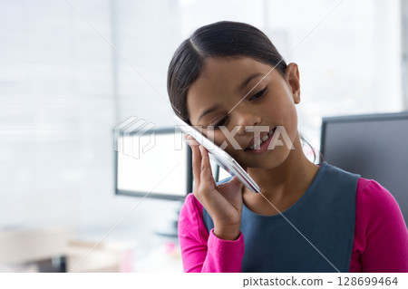 Talking girl standing in home office holding smartphone by computer monitors and desk, copy space Talking girl standing in home office holding smartphone by computer monitors and desk, copy space 128699464