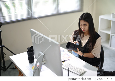 Female photographer carefully cleaning a camera lens at her modern editing workspace Female photographer carefully cleaning a camera lens at her modern editing workspace 128699627