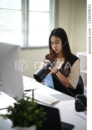 Young female photographer cleaning camera equipment in a bright office Young female photographer cleaning camera equipment in a bright office 128699631