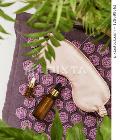 Self care concept with mask for sleep, dropper bottles with natural oils on massage relax mat with home plants. Concept of Relaxing at home, Me time, take care, healthy and good sleeping. Flat lay Self care concept with mask for sleep, dropper bottles with natural oils on massage relax mat with home plants. Concept of Relaxing at home, Me time, take care, healthy and good sleeping. Flat lay 128699662