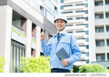 Middle-aged man in work clothes pointing 128700202