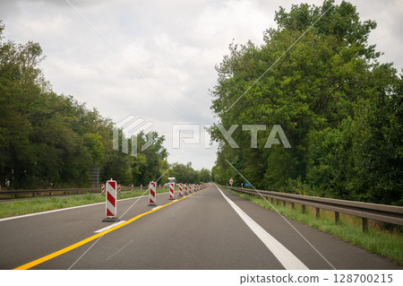 Traffic barriers and lane markings on rural highway during road construction in summer 128700215