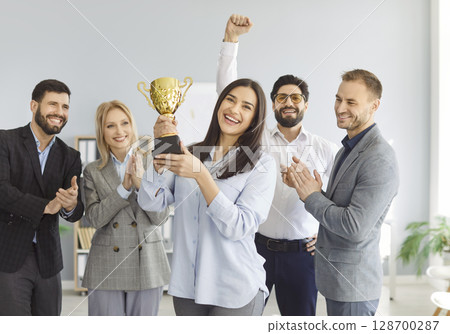 Happy business team holding golden trophy cup, clapping and celebrating great hard work success. Happy business team holding golden trophy cup, clapping and celebrating great hard work success. 128700287