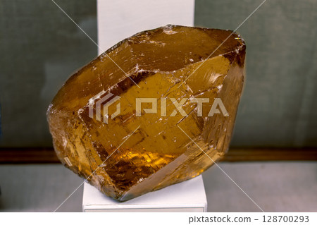 Citrine quartz crystal with a vibrant yellow hue, showcasing its natural beauty and raw form on stand 128700293