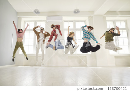Joyful group of young people students and sunglasses jumping together and having fun indoors 128700421