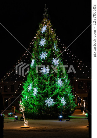 Christmas tree decorated with lights and decorations in the town square at night Christmas tree decorated with lights and decorations in the town square at night 128700508