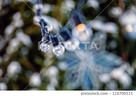 garland of light bulbs on defocused festive lights background, shallow depth of field, copy space 128700515
