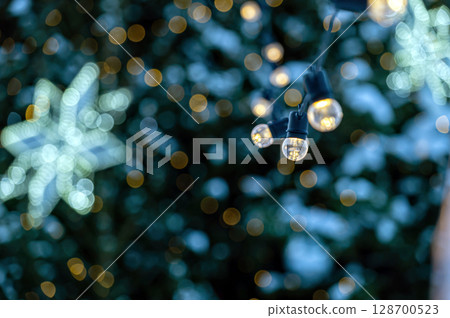garland of light bulbs on defocused festive lights background, shallow depth of field, copy space 128700523
