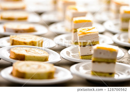 rows of cake desert on white dish row on table for break after meeting 128700562