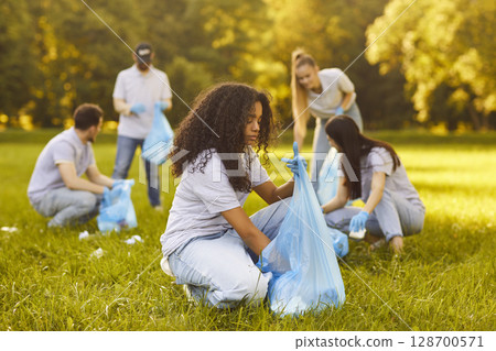Focused Volunteers Collecting Trash In City Park 128700571