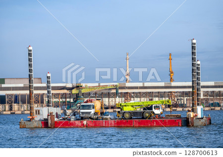 floating platform with crane for hydrotechnical works and concrete mixer trucks on deck 128700613