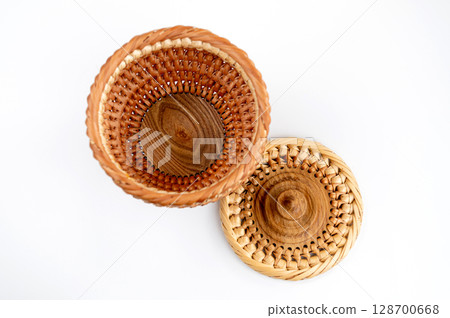 A wicker tray for fruits or sweets on a white background with a wooden handle A wicker tray for fruits or sweets on a white background with a wooden handle 128700668