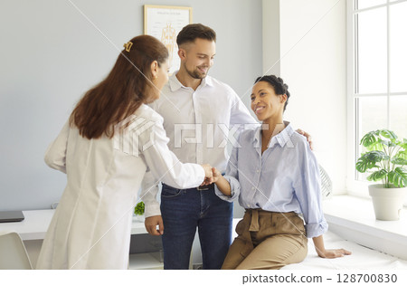 Couple consulting doctor gynecologist about planning future baby, shaking hand, having consultation 128700830