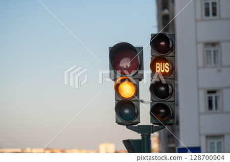 Traffic lights show red and green signals, indicating movement for vehicles and buses. 128700904