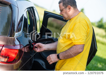 worried and surprised emotional man at open car fuel tank, fuel price rise concept 128701076