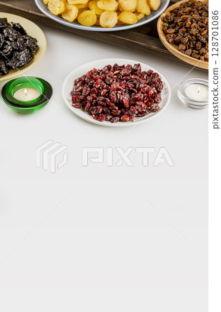 Ramadan food vertical banner with dried apricots, cranberries, raisins, and prunes on plates on white background with copy space. Dry fruits assortment. Healthy sweet snack - mix of organic dry fruits Ramadan food vertical banner with dried apricots, cranberries, raisins, and prunes on plates on white background with copy space. Dry fruits assortment. Healthy sweet snack - mix of organic dry fruits 128701086