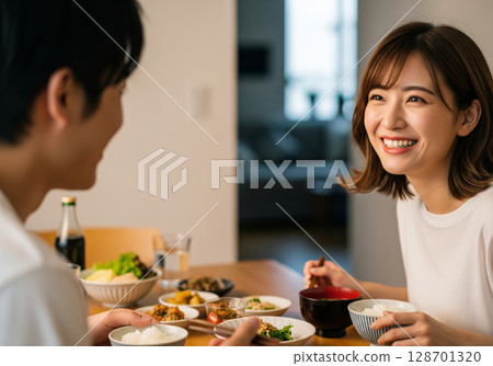 餐桌上歡笑，氣氛融洽！一對身穿白色T恤的情侶的幸福瞬間 128701320