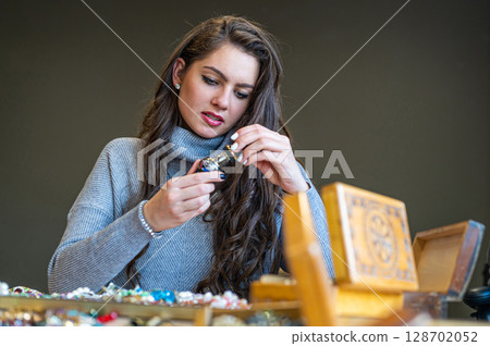 reflection of a woman in mirror choosing and trying different jewelry, soft focus, closeup reflection of a woman in mirror choosing and trying different jewelry, soft focus, closeup 128702052