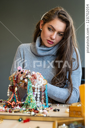 reflection of a woman in mirror choosing and trying different jewelry, soft focus, closeup reflection of a woman in mirror choosing and trying different jewelry, soft focus, closeup 128702054