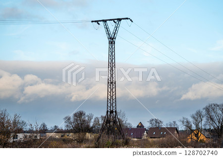 A metal support for a power line on the background of a summer cottage village. 128702740