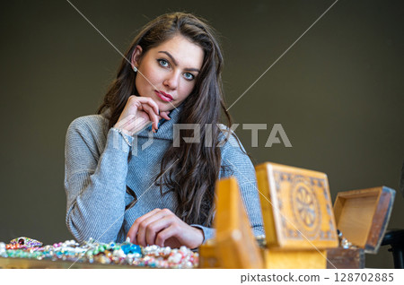 reflection of a woman in mirror choosing and trying different jewelry, soft focus, closeup 128702885