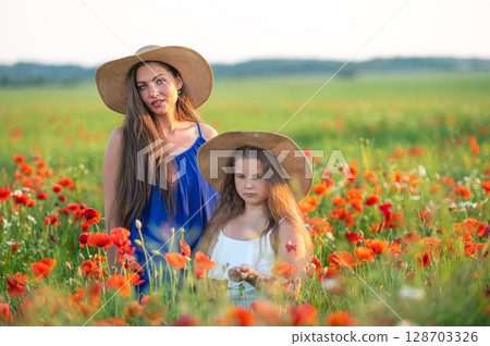 beautiful young woman with girl in straw hats in poppy field, happy family having fun in nature beautiful young woman with girl in straw hats in poppy field, happy family having fun in nature 128703326