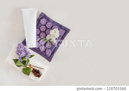 Spa relax flat lay with massage mat, dropper bottle with serum on white towel with lilac flowers and cosmetic tube on light grey background. Mock up of beauty product. Relaxing at home. Copy space Spa relax flat lay with massage mat, dropper bottle with serum on white towel with lilac flowers and cosmetic tube on light grey background. Mock up of beauty product. Relaxing at home. Copy space 128703388
