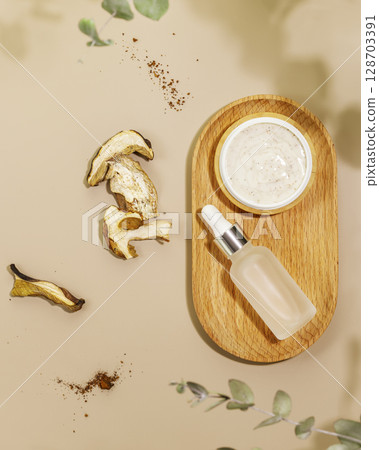 Natural mushrooms cosmetics. Mushroom scrub and organic serum on wooden tray with dry mushrooms. Wellness, skin care and spa relax treatment concept. Flat lay Natural mushrooms cosmetics. Mushroom scrub and organic serum on wooden tray with dry mushrooms. Wellness, skin care and spa relax treatment concept. Flat lay 128703391