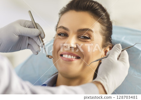 Unrecognizable dentist examining teeth of young woman patient in private clinic Unrecognizable dentist examining teeth of young woman patient in private clinic 128703481