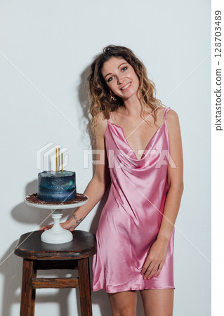 woman in dress standing with pastry cake prepared for holiday 128703489