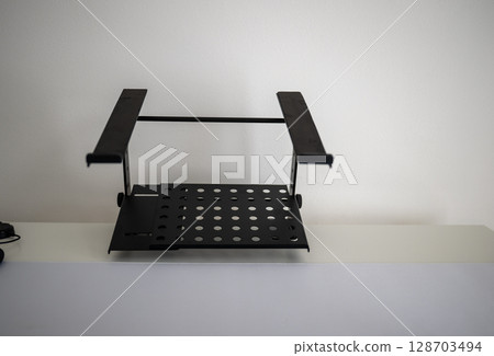 Adjustable metal laptop stand on white desk in minimal home office Adjustable metal laptop stand on white desk in minimal home office 128703494