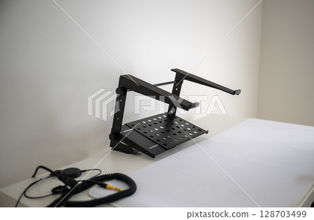 Adjustable metal laptop stand on white desk in minimal home office  128703499