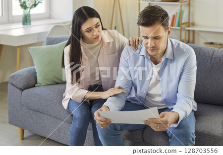 Frustrated desperate man checking bills for payments, holding health test result, getting upset 128703556