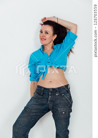 Beautiful brunette woman in jeans and blue shirt on white background 128703559