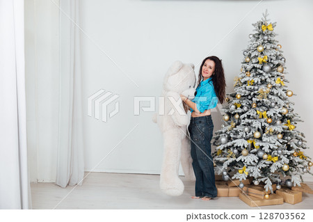 woman in jeans at Christmas tree with toys and gifts decorated for new year 128703562