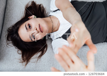 brunette woman lying on a gray office sofa in a white room 128703684